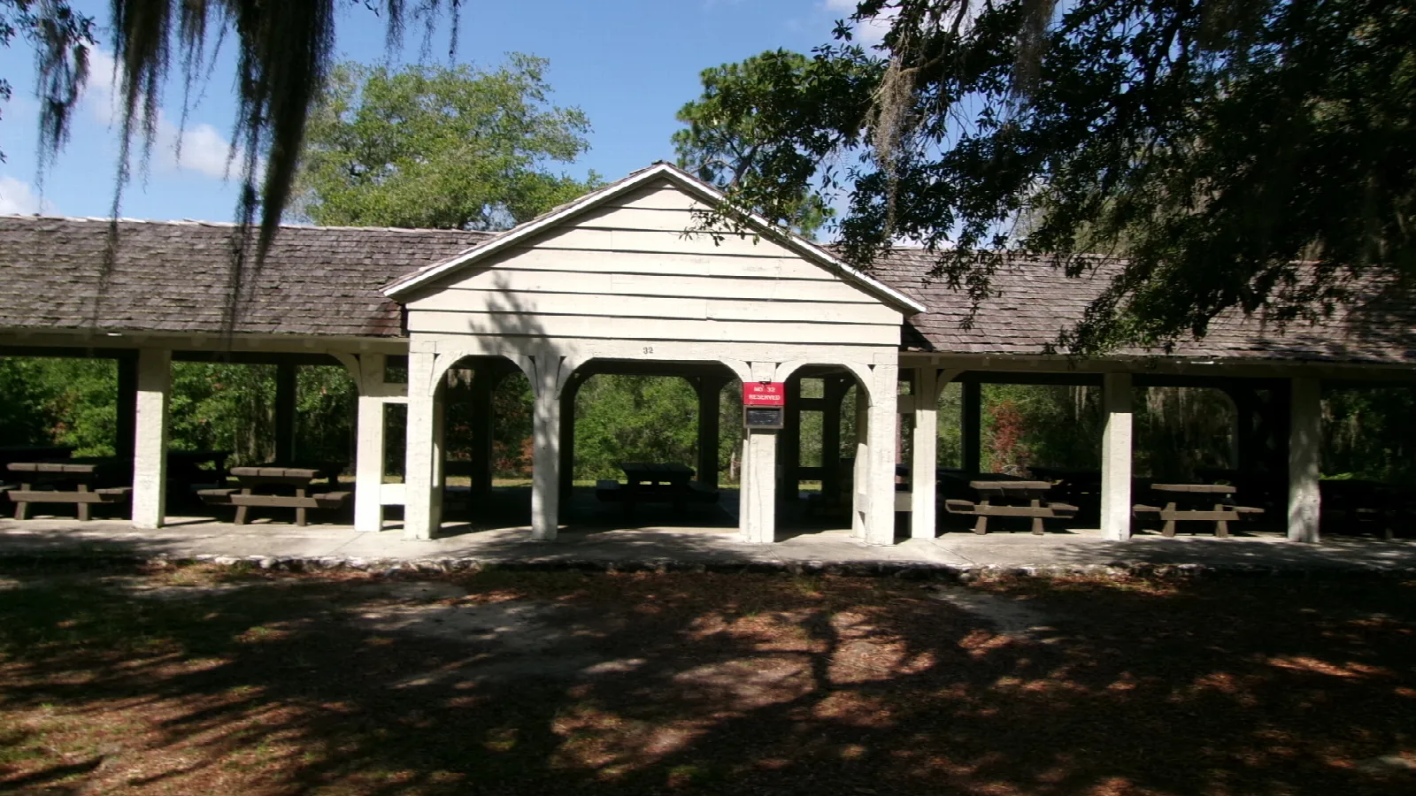 Open picnic pavilion with tables under trees