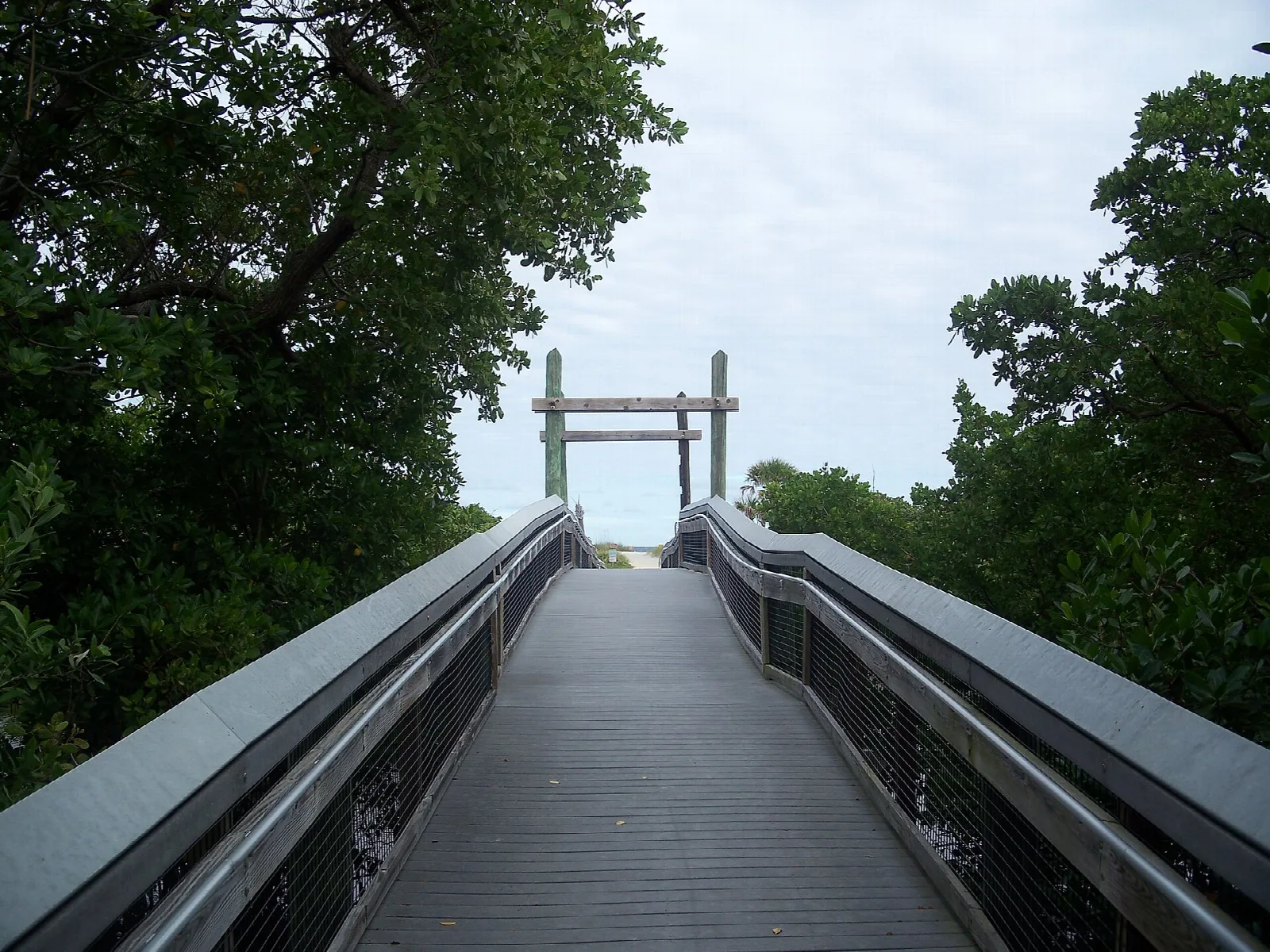 Boardwalk with railings leading toward a wooden gate