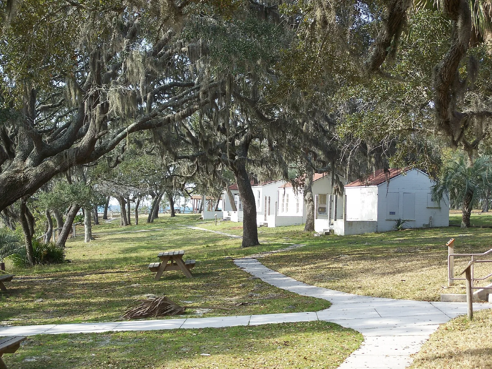 Paved path through oaks toward white cabins