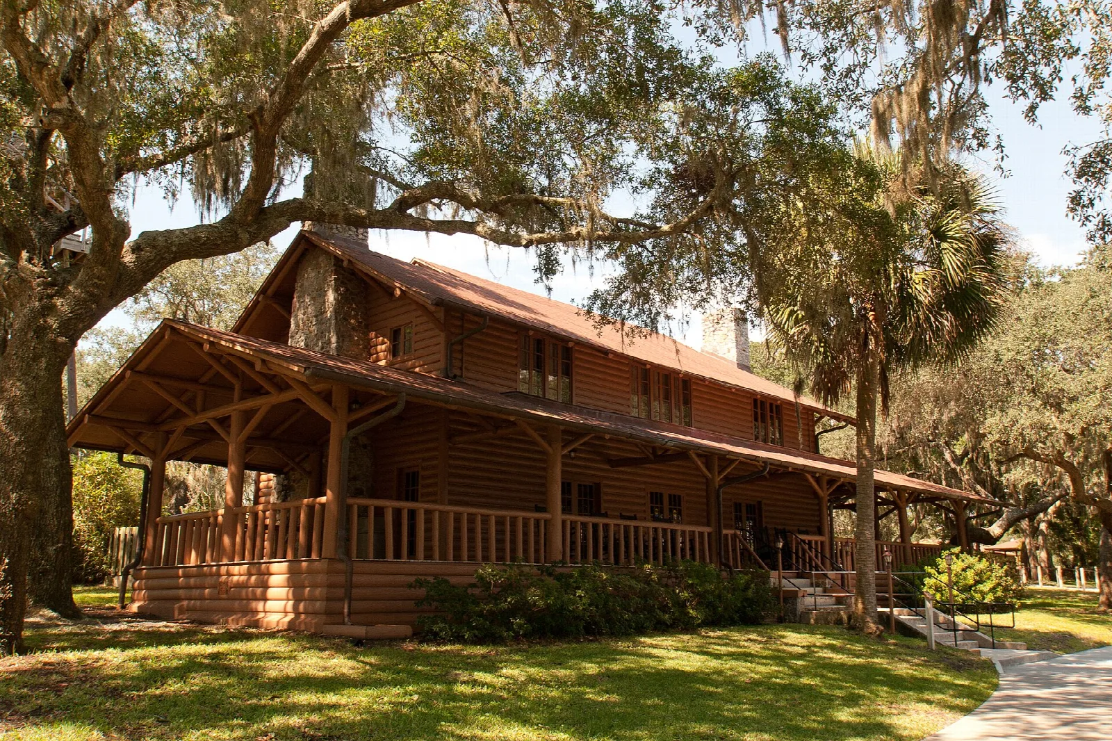 Large wooden lodge with a wide porch under live oaks