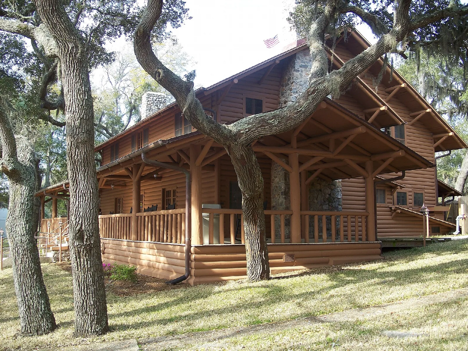 Wooden cabin with a covered porch under oaks