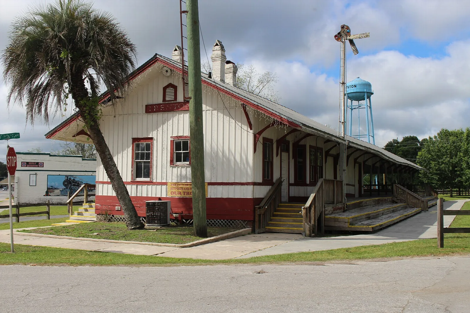 White and red wooden railroad depot with a porch and palm