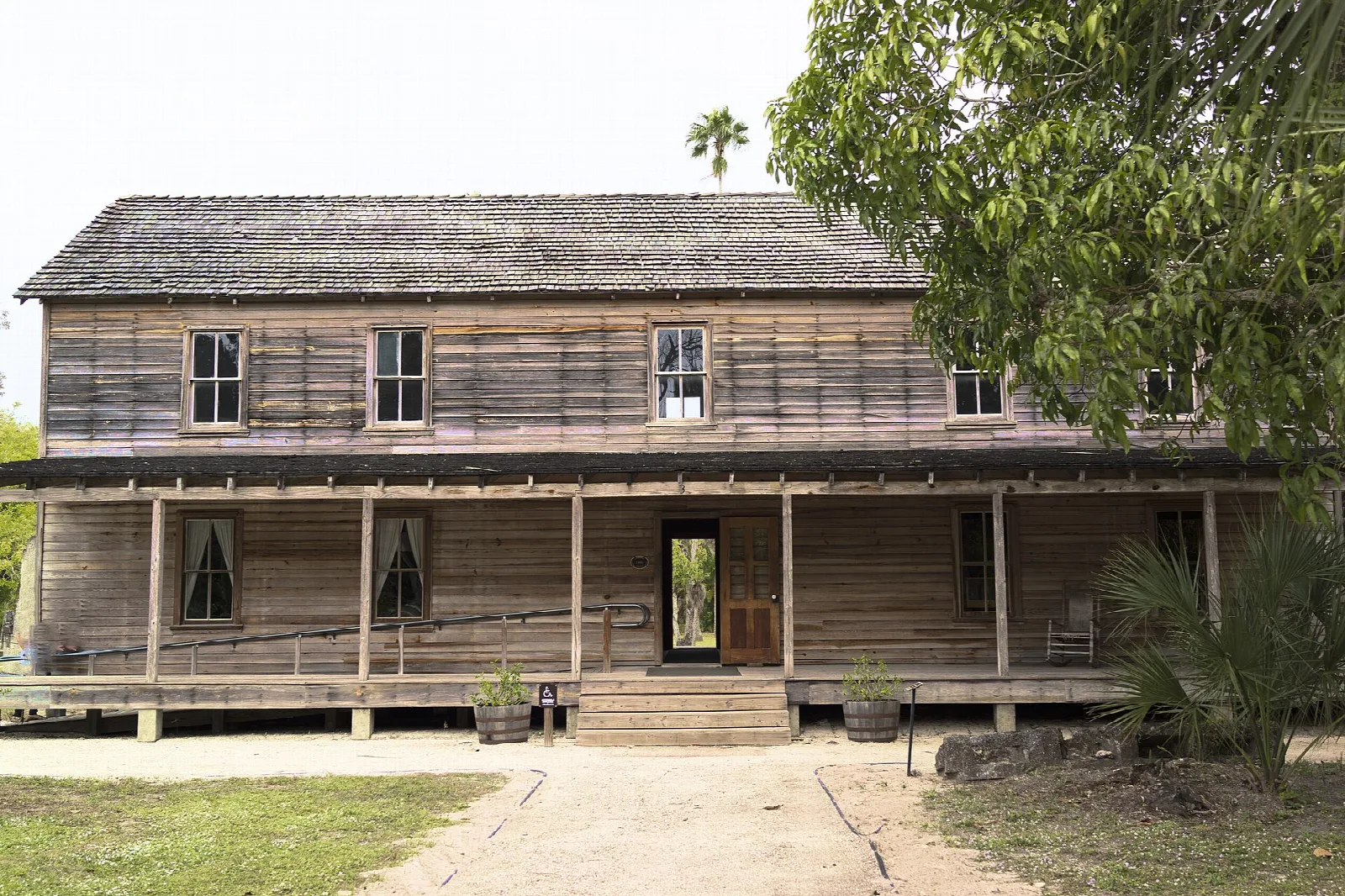 Long weathered wooden building with a porch and wooden steps