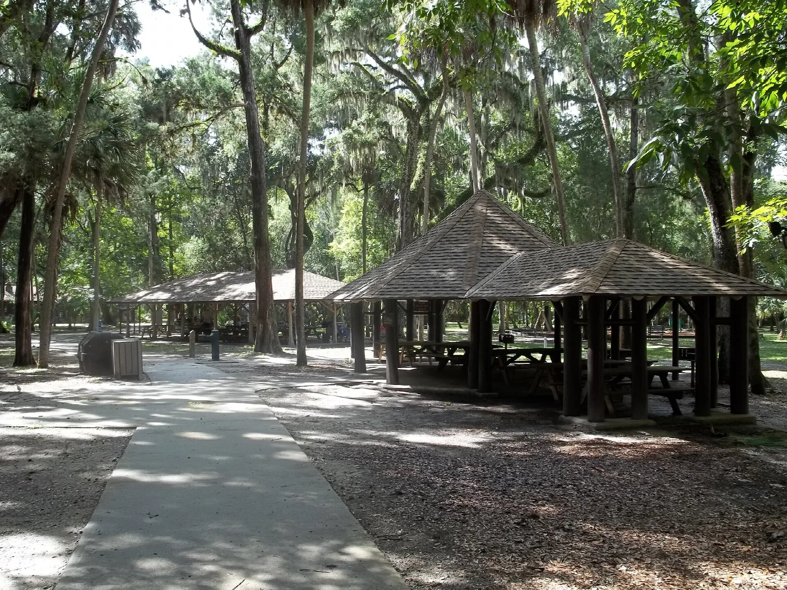 Thatched-roof picnic pavilions among oaks and palms