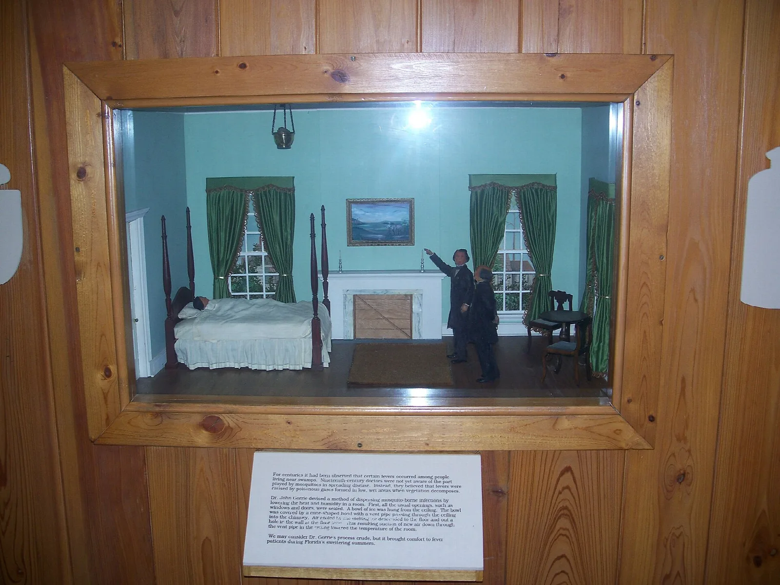 Display case diorama of a bedroom with a figure inside
