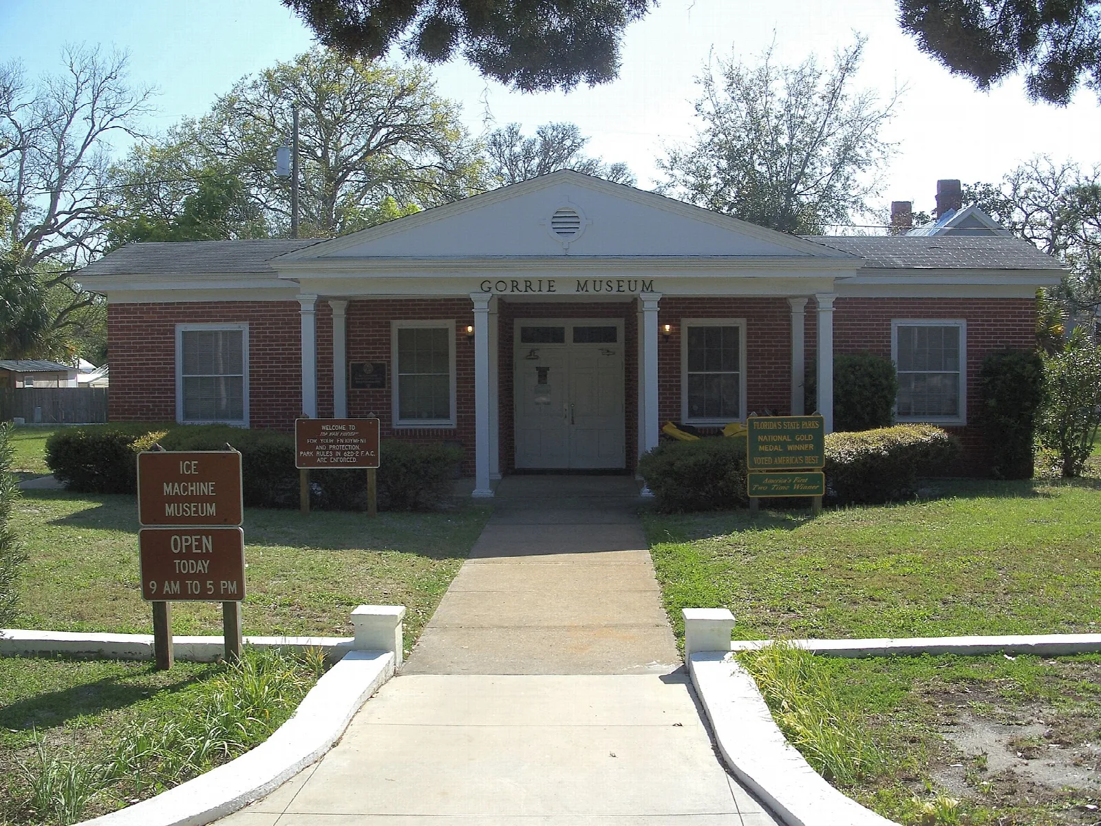 Brick museum building with white columns and a lawn in front