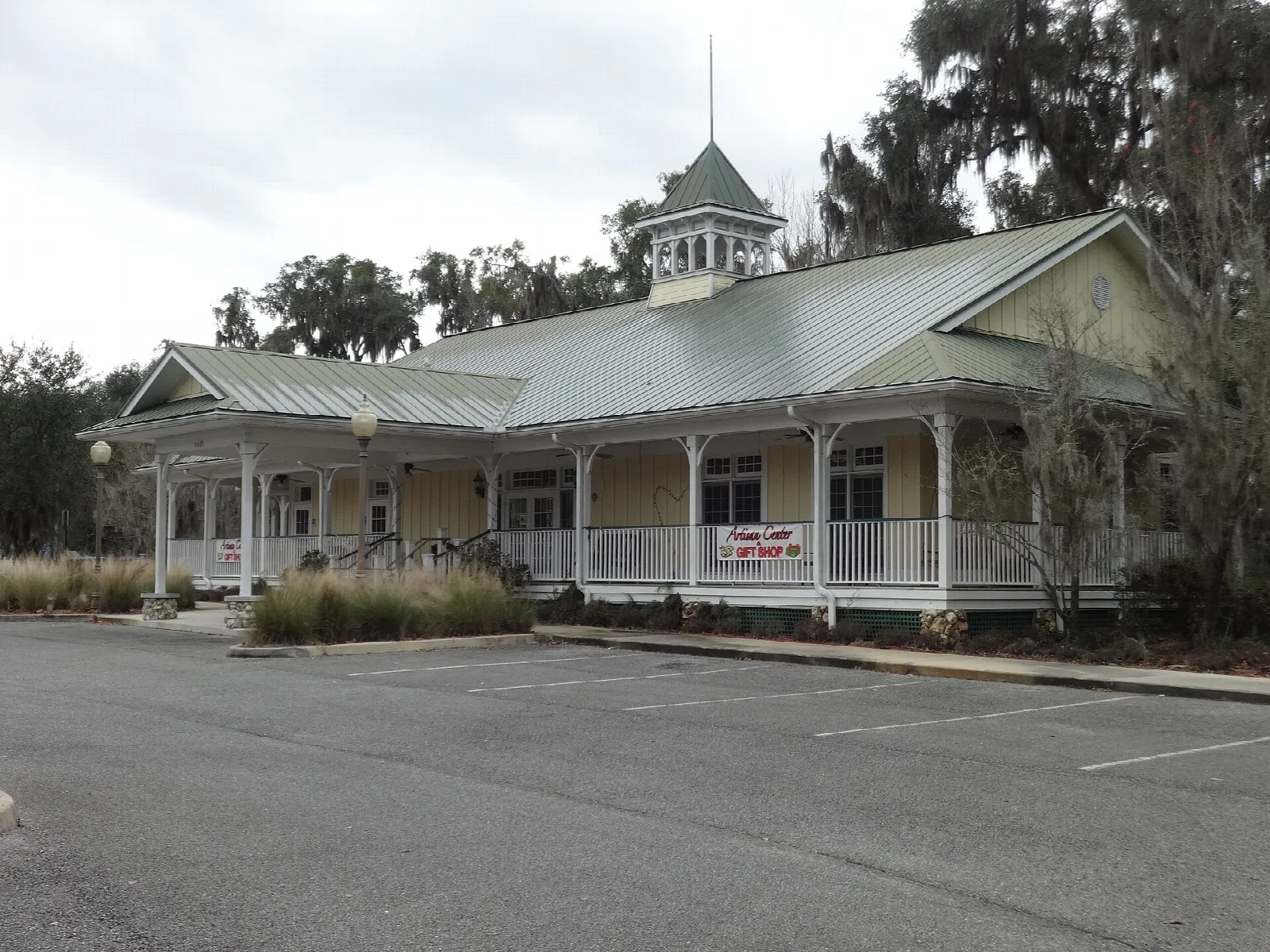 Long low building with a porch, cupola and metal roof
