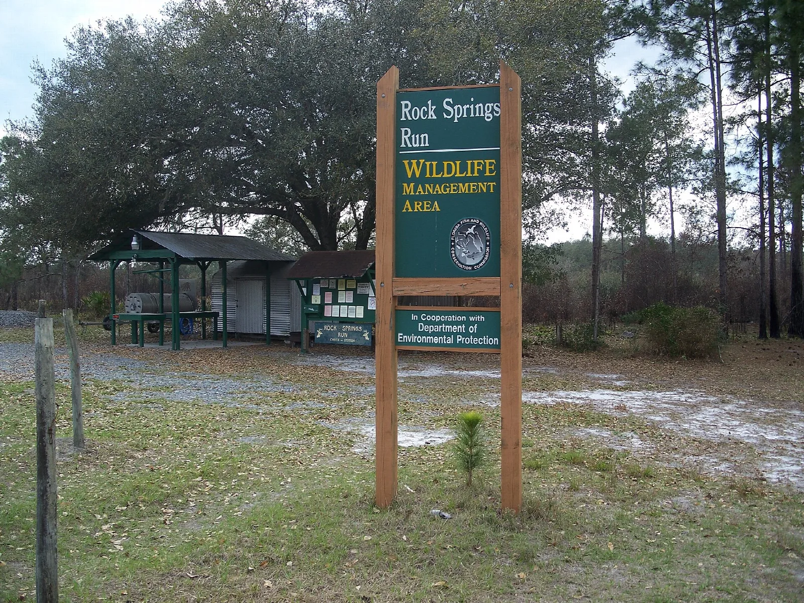 Wooden sign at a check station with a small shelter behind