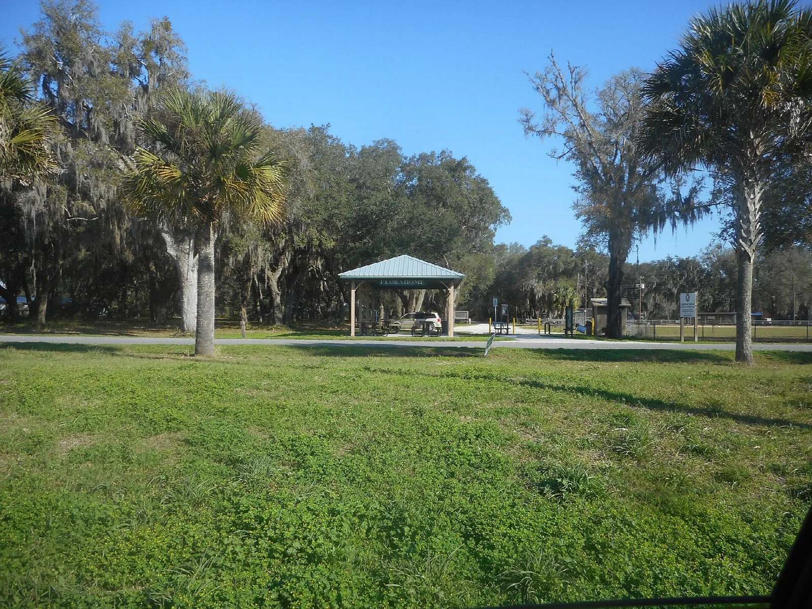 Open picnic shelter on a lawn under oaks and palms