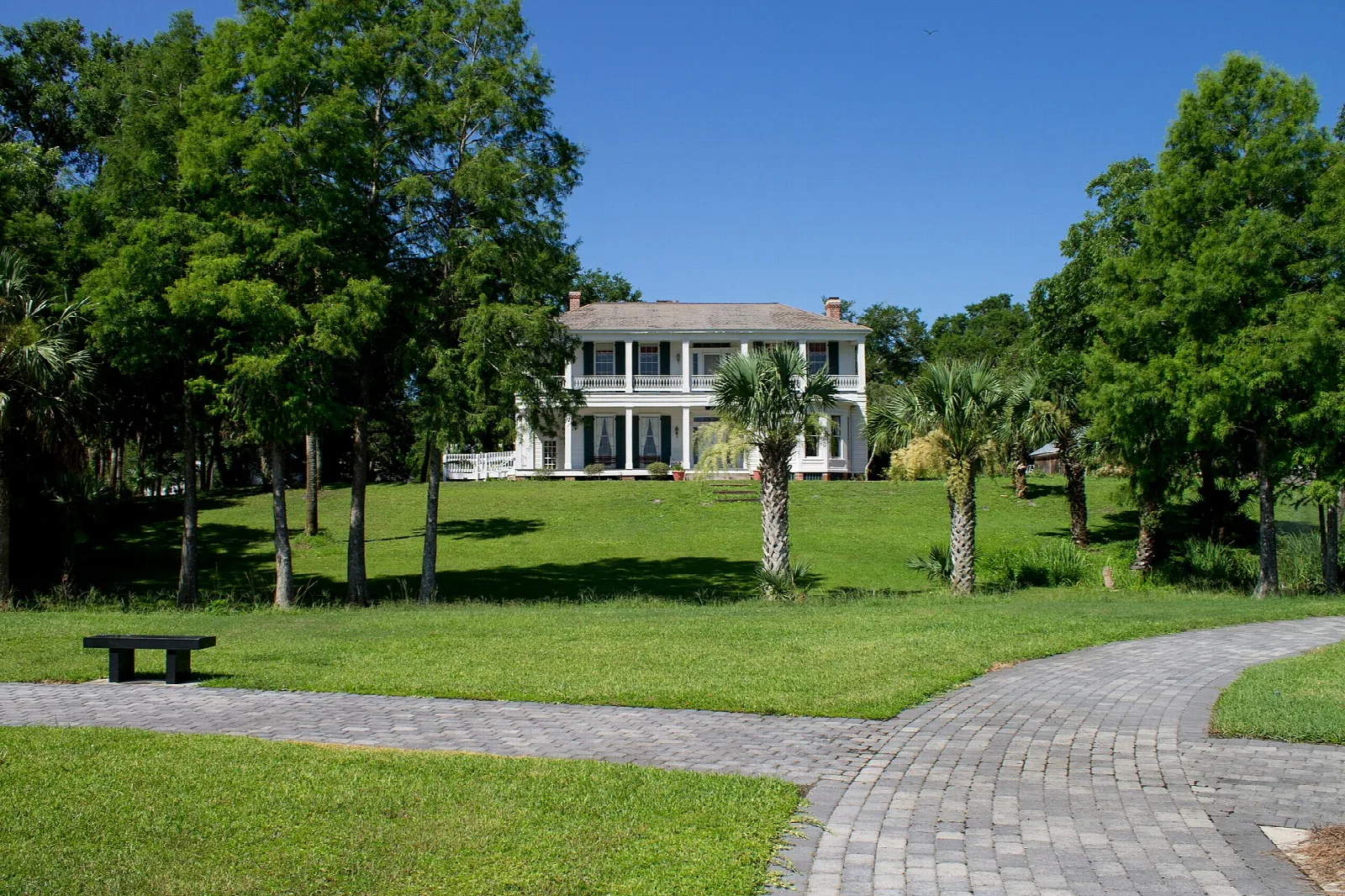 Brick path across a green lawn toward a white house