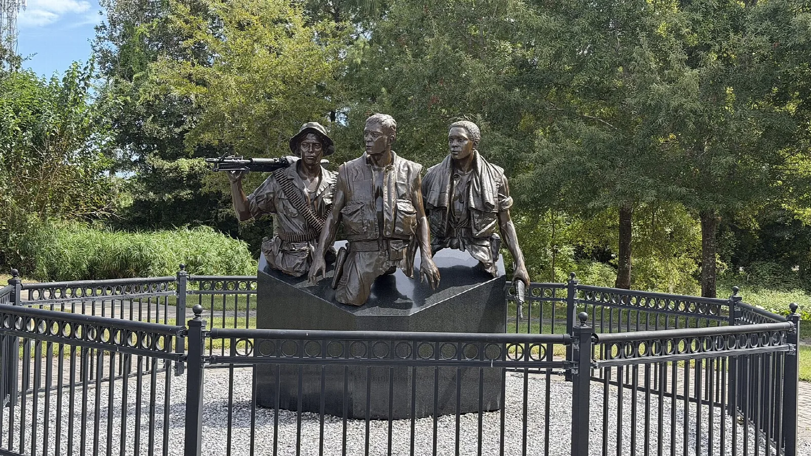 Bronze statue of three soldiers inside an iron fence