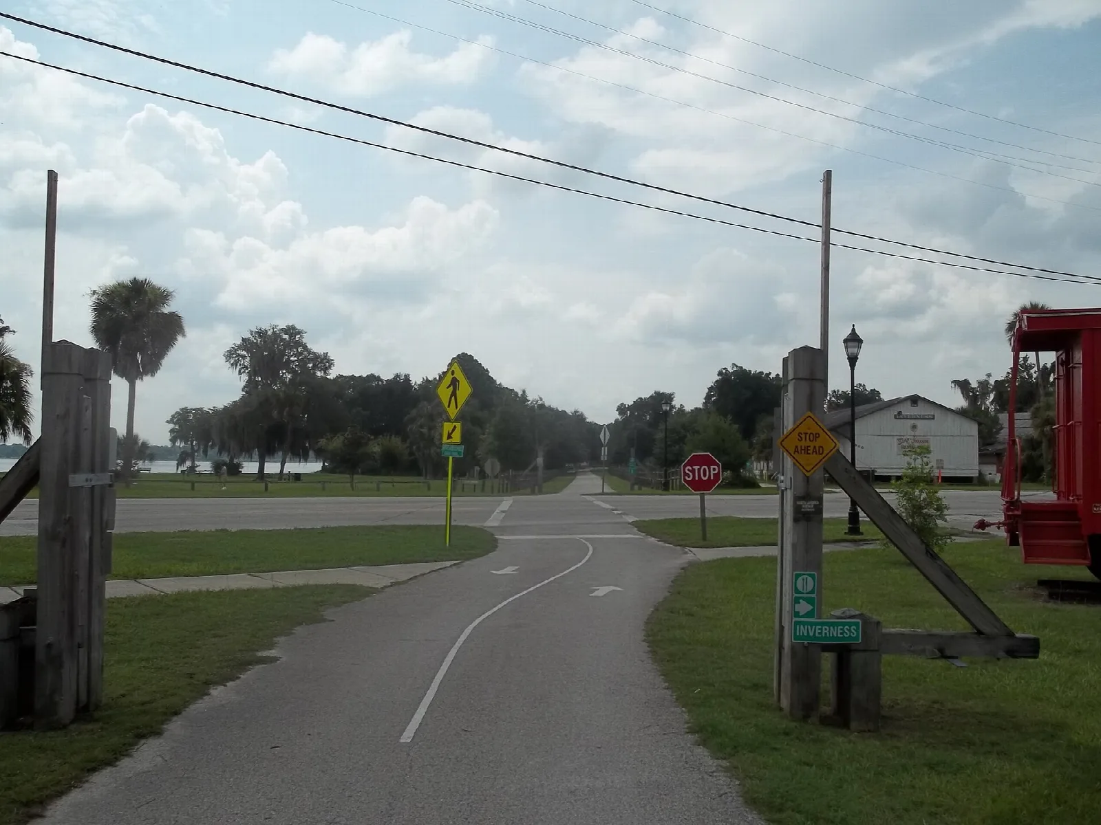 Paved trail crossing a road beside a trail marker