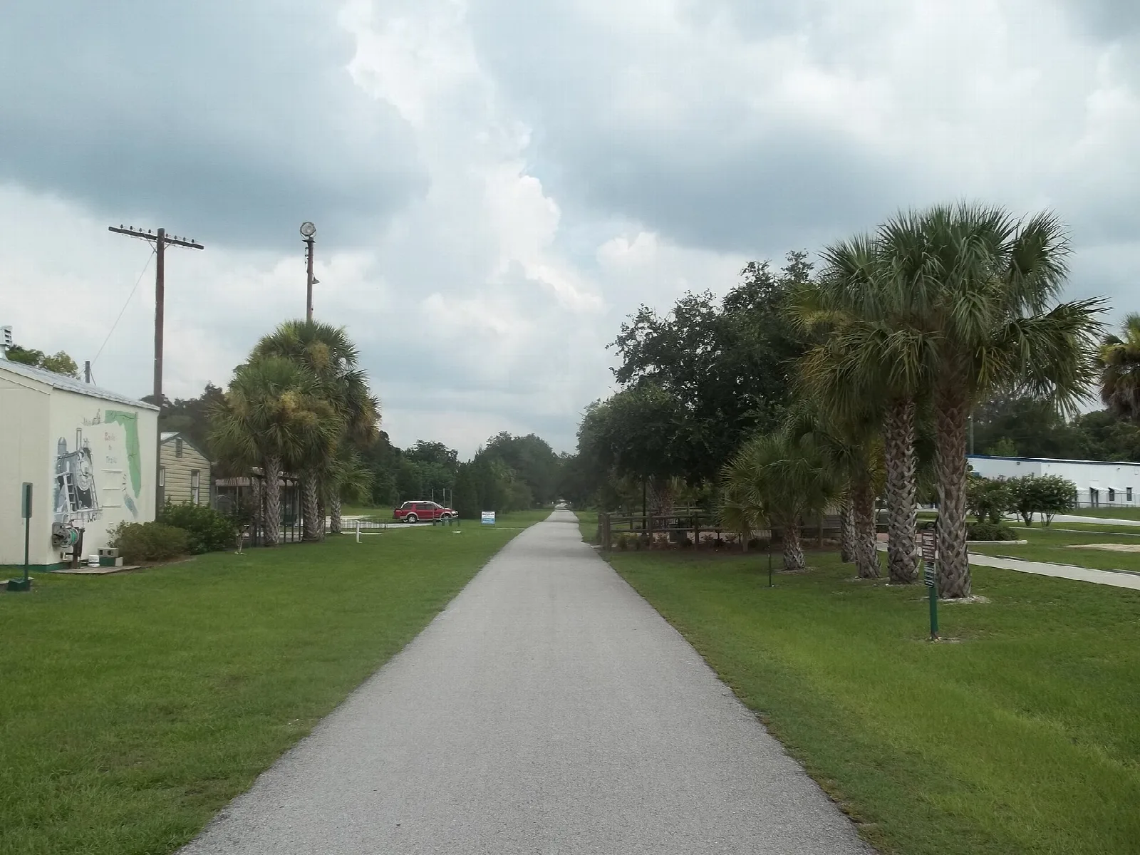 Paved trail running straight between lawns and palms
