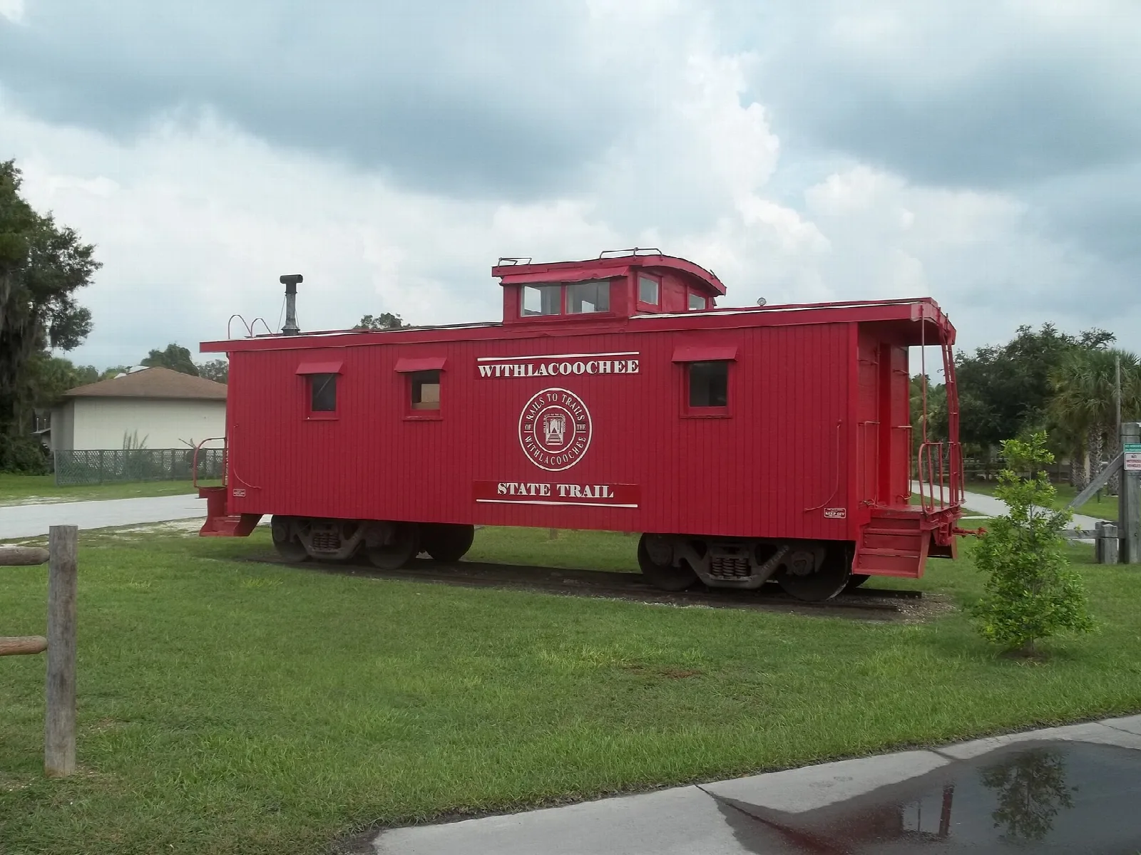 Red caboose on a lawn beside the trail