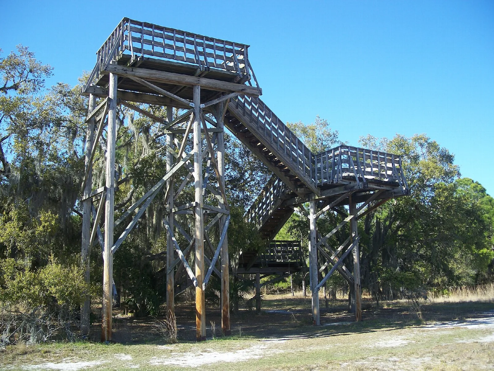 Tall wooden observation tower beside a sandy lot