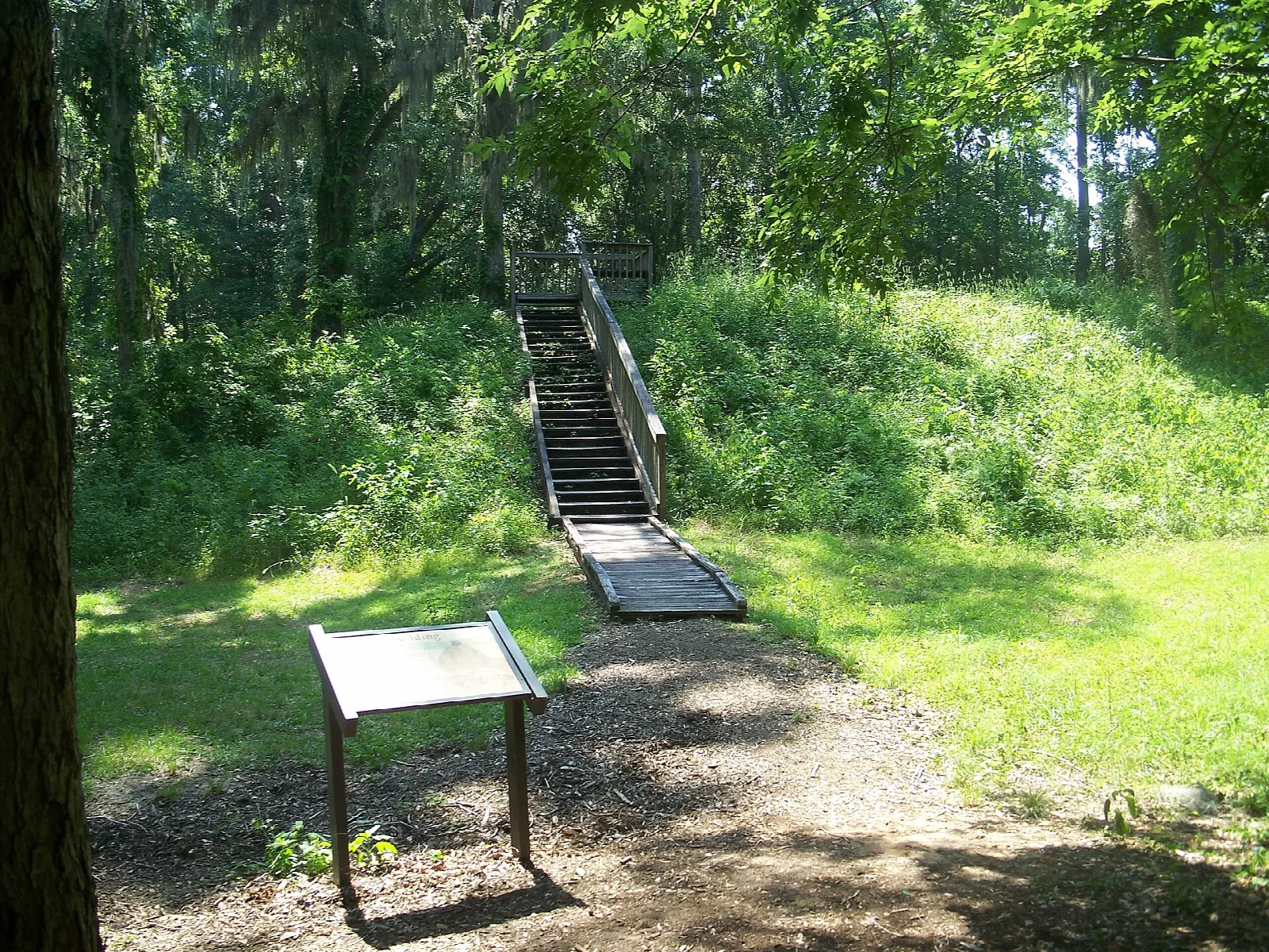 Stairway up a grassy mound with an information sign in front