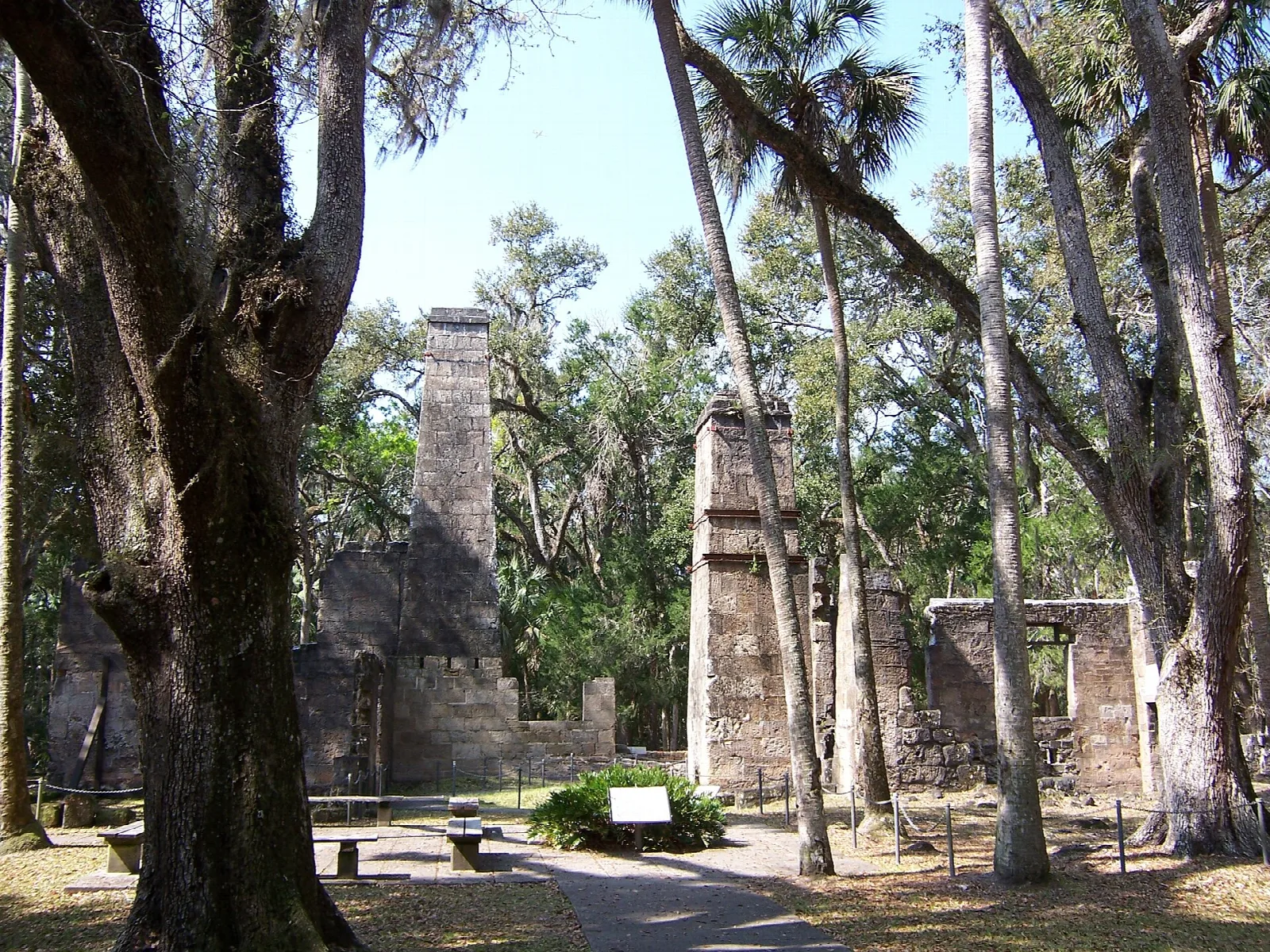 Stone mill ruins beyond a trail under big oaks