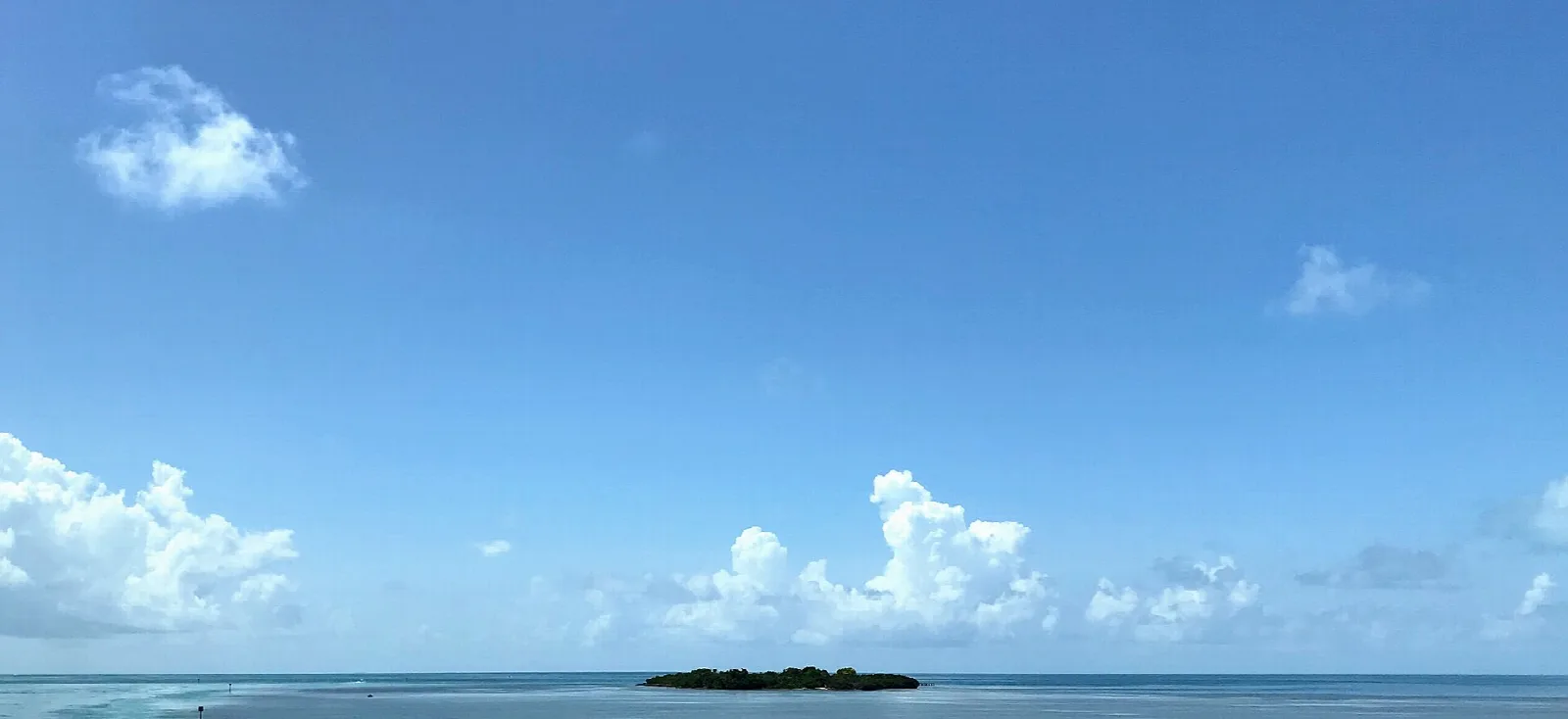 Small dark island on the horizon under a blue sky