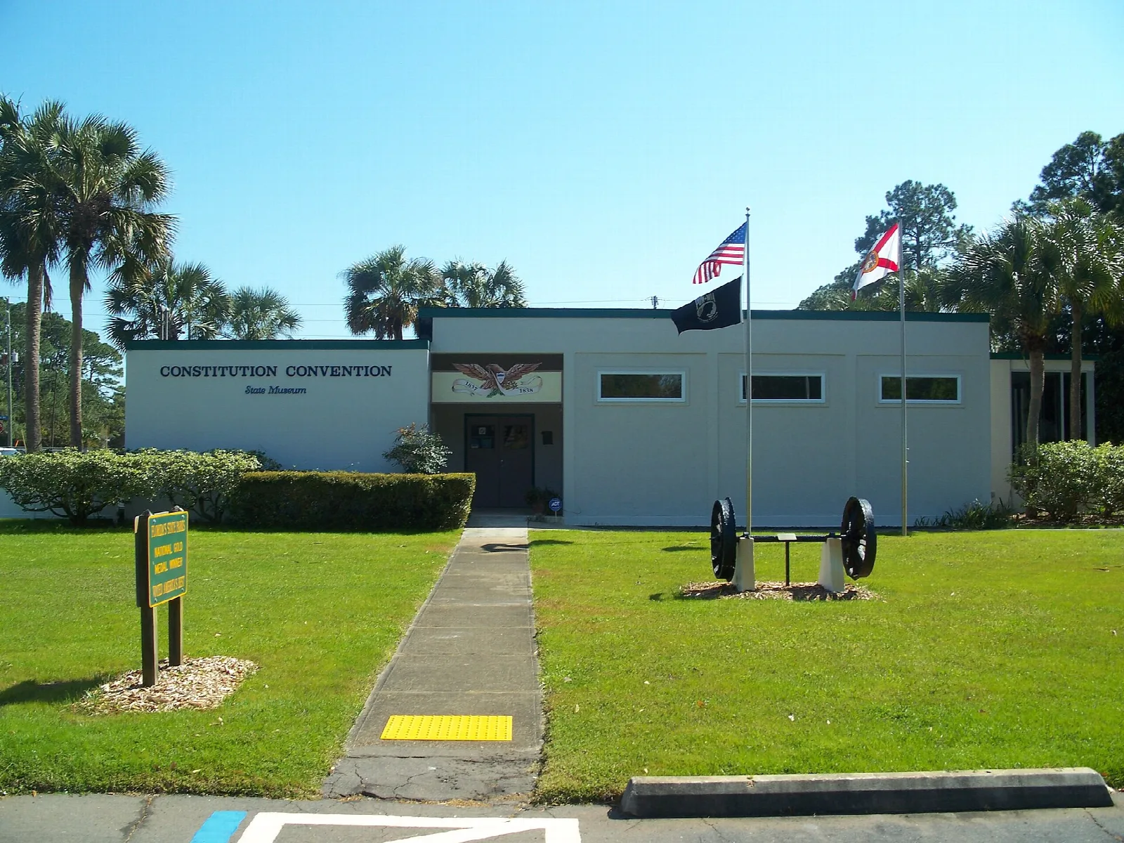 Low white museum building with flags and a green lawn