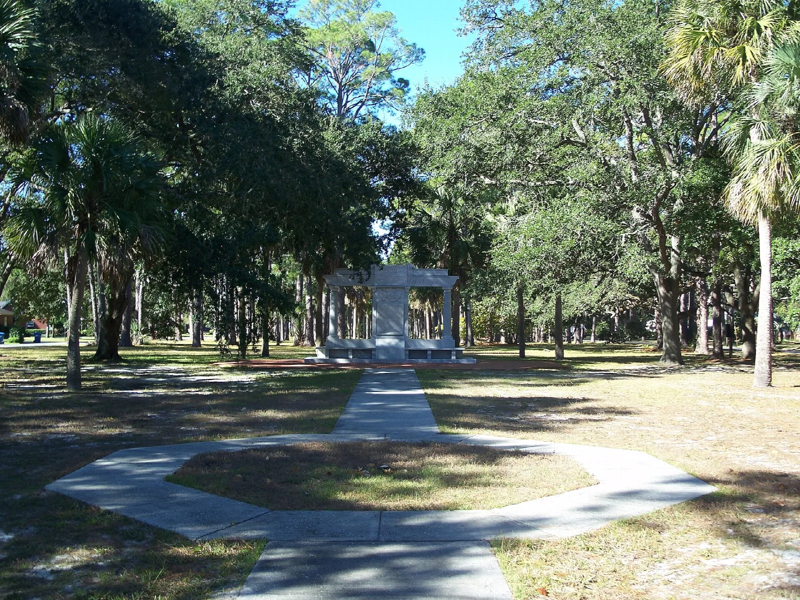 Stone monument at the end of a curved walkway in a park of oaks