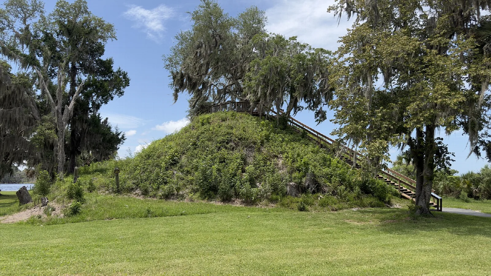 Mound with a railed stairway under live oaks beside a lawn