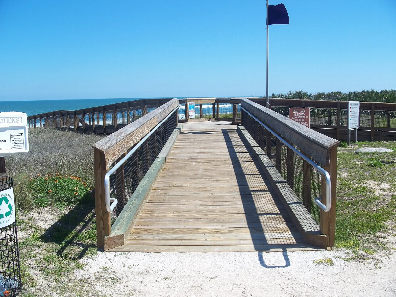 Wooden boardwalk with railings leading to the beach