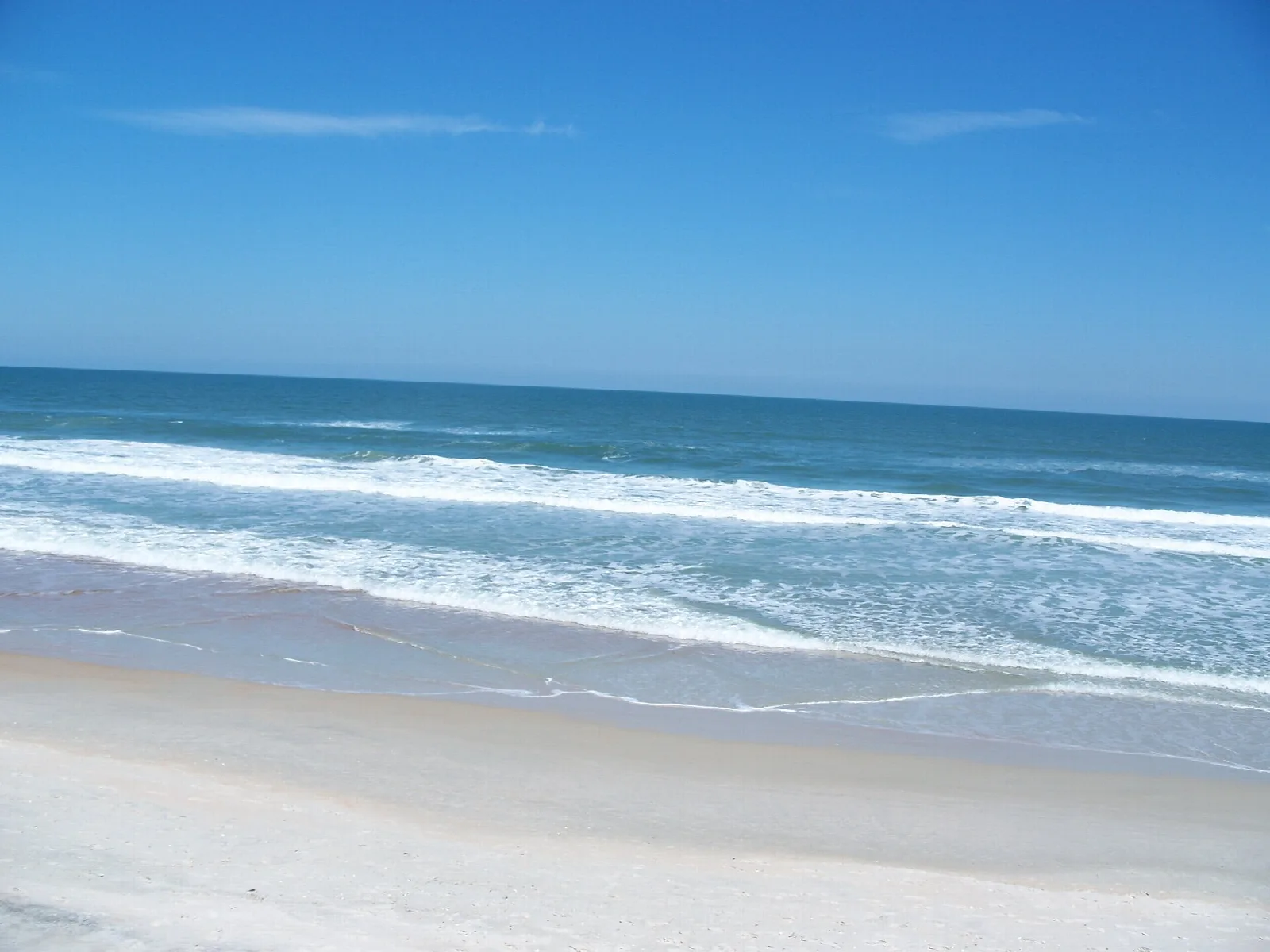 Blue ocean surf on a pale sandy beach