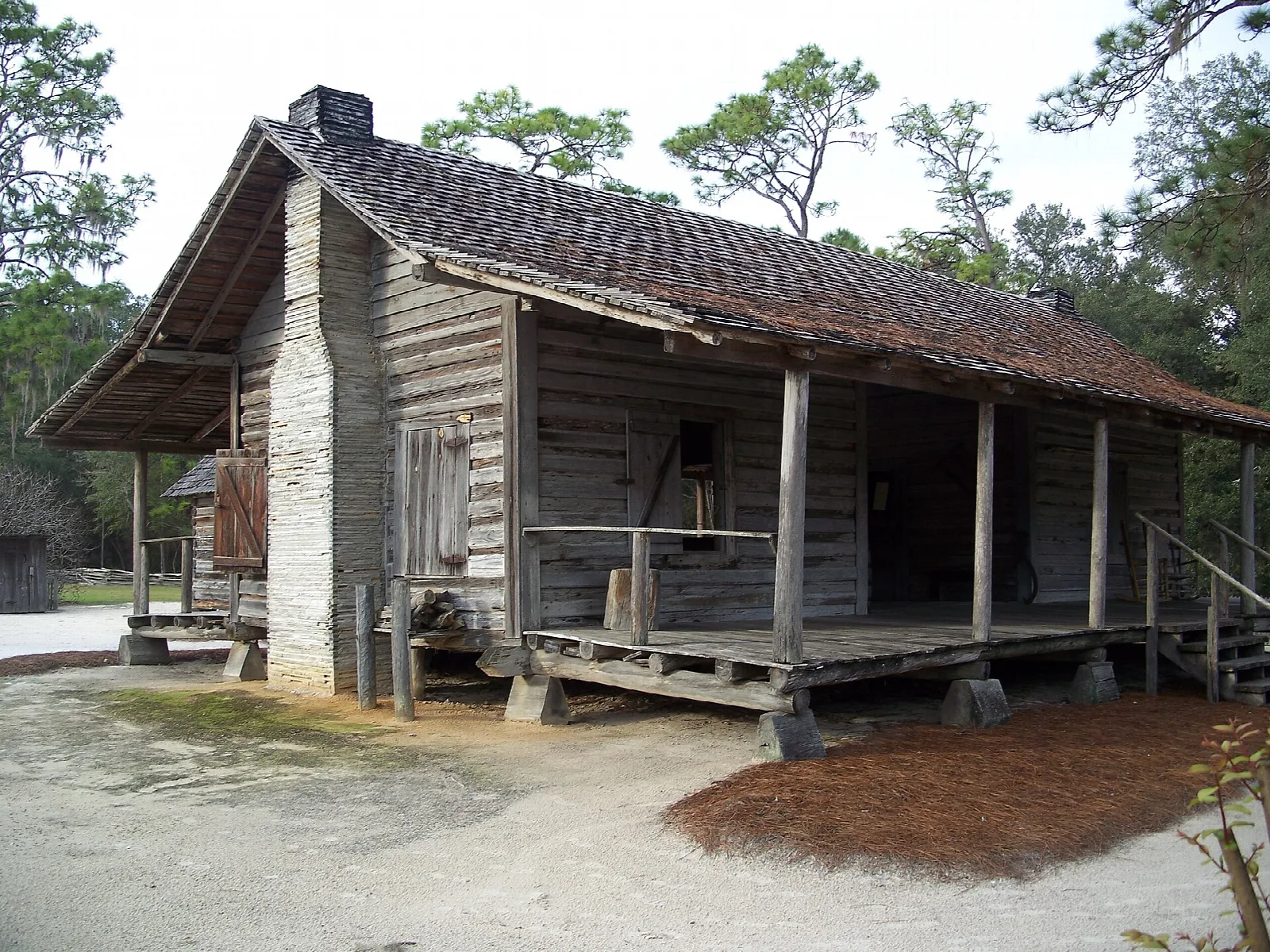Old wooden cabin with a long front porch and stone chimney