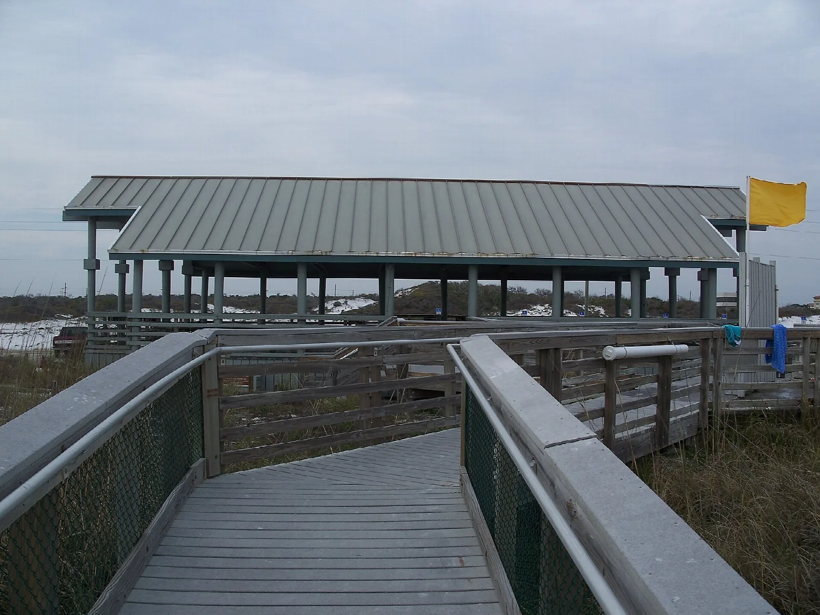 Wooden boardwalk leading to a metal-roofed beach pavilion