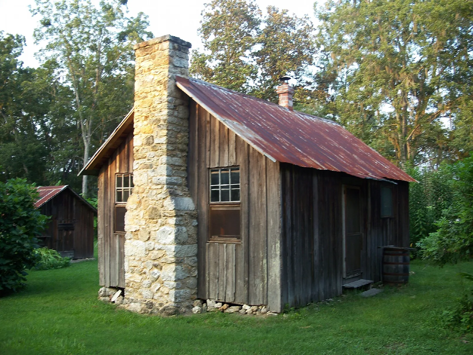 Old wooden farm building with a stone chimney and rusty tin roof