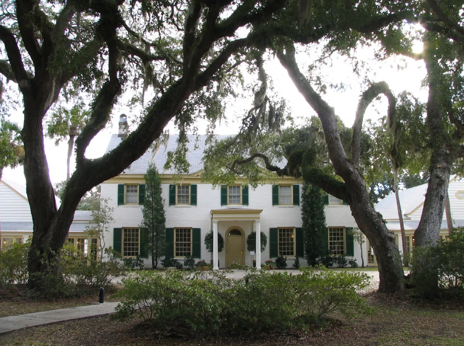 White clubhouse framed by spreading live oaks