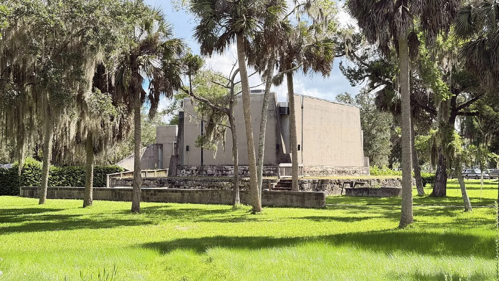 Museum building seen across a green lawn with palms