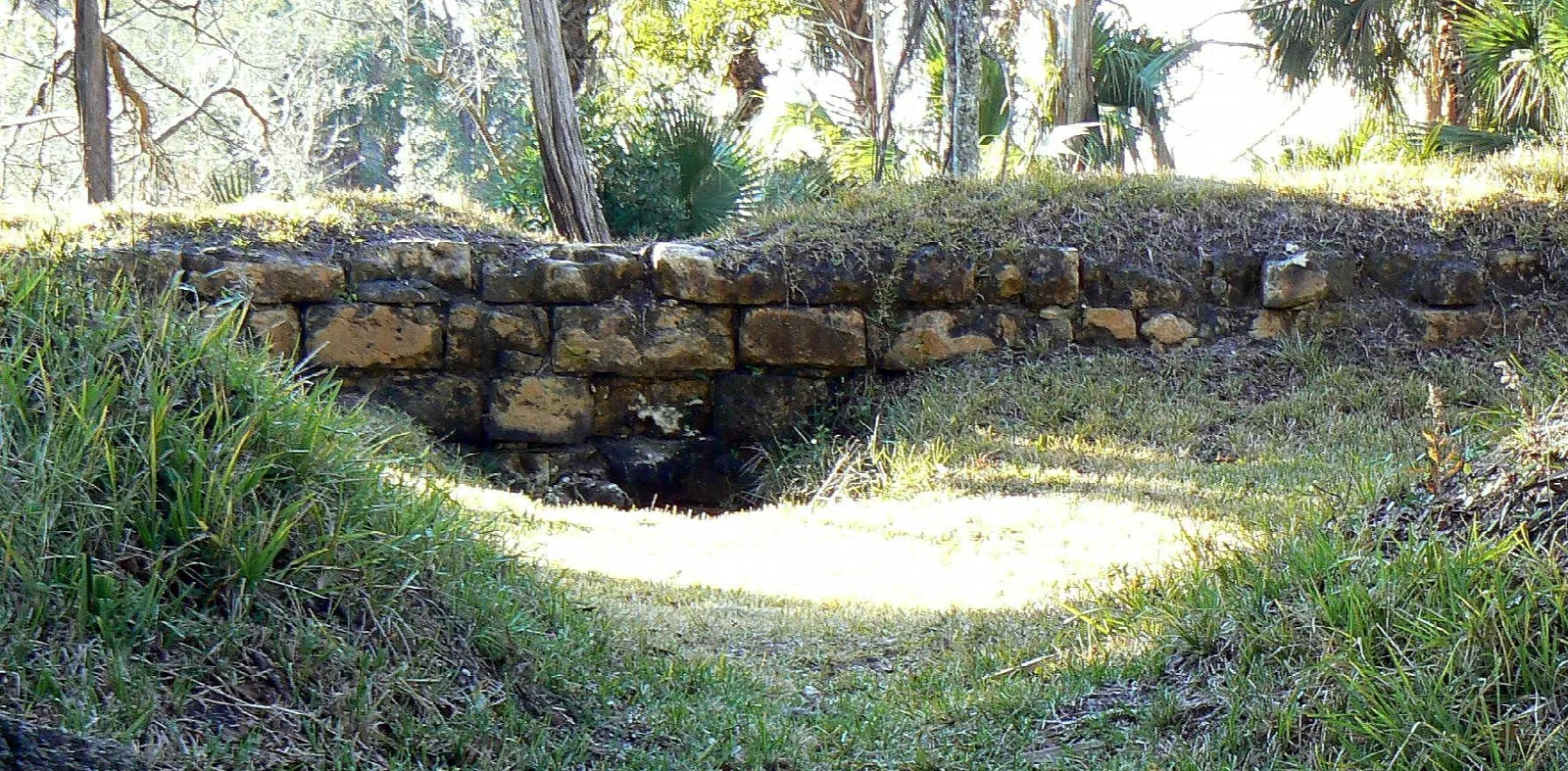 Low stone wall and earth mound of the old fort in sun