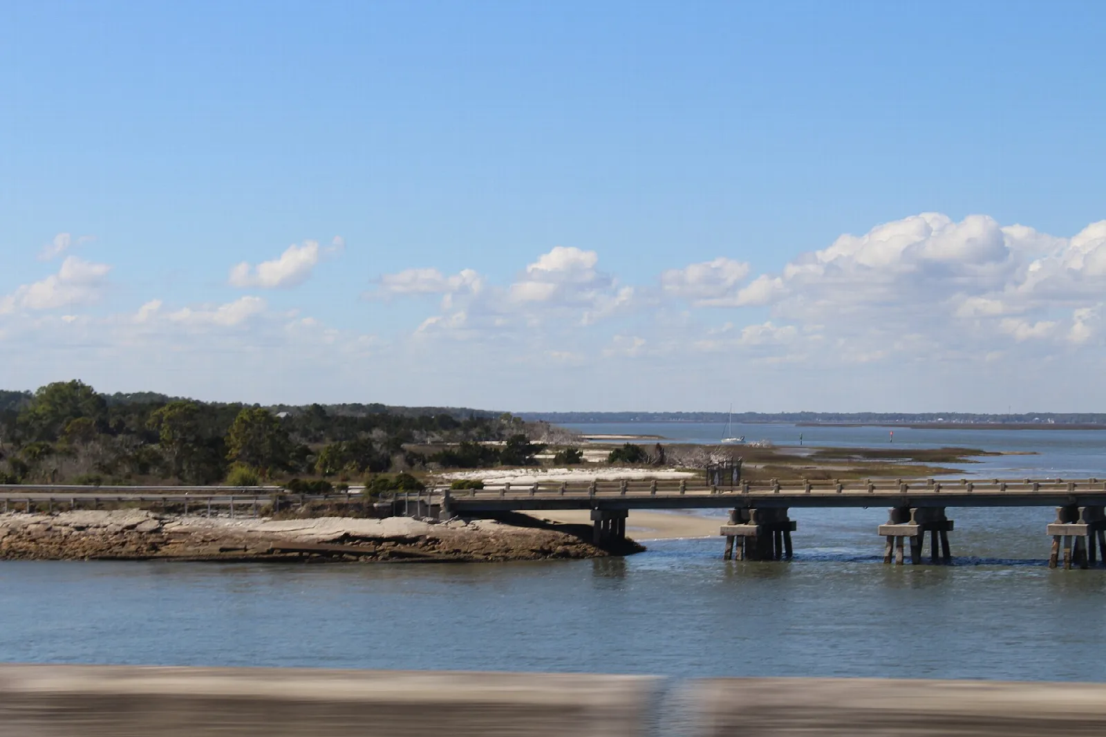 Low bridge over water beside a marsh and tree line