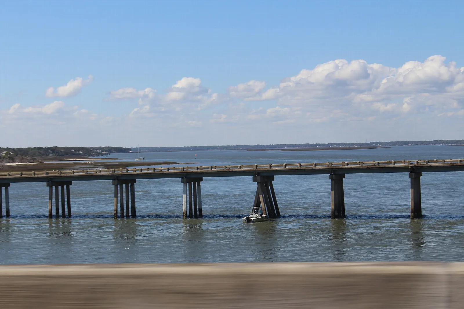 Long low bridge over blue water with clouds above