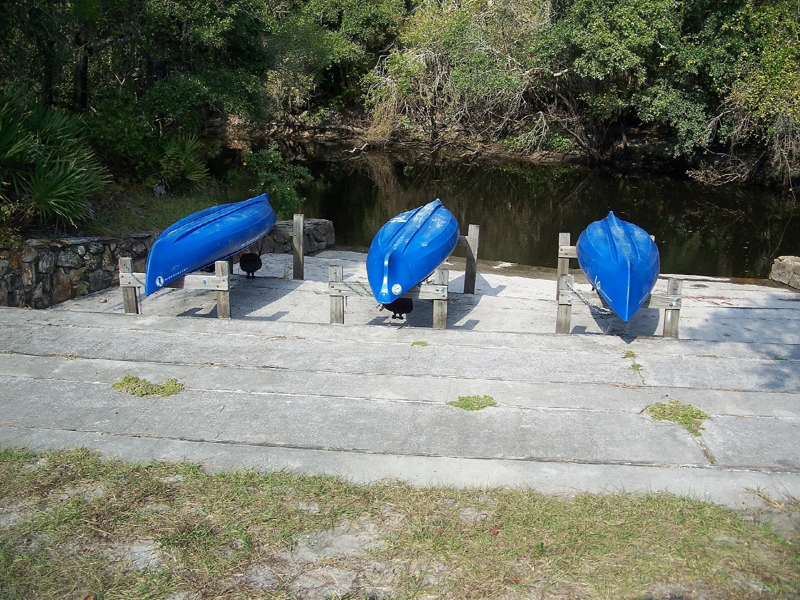 Blue canoes on a concrete ramp beside the river
