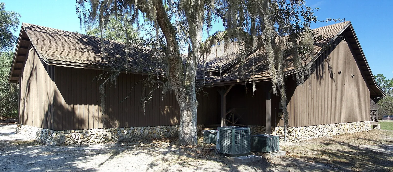 Brown wood visitor building under moss-draped oaks