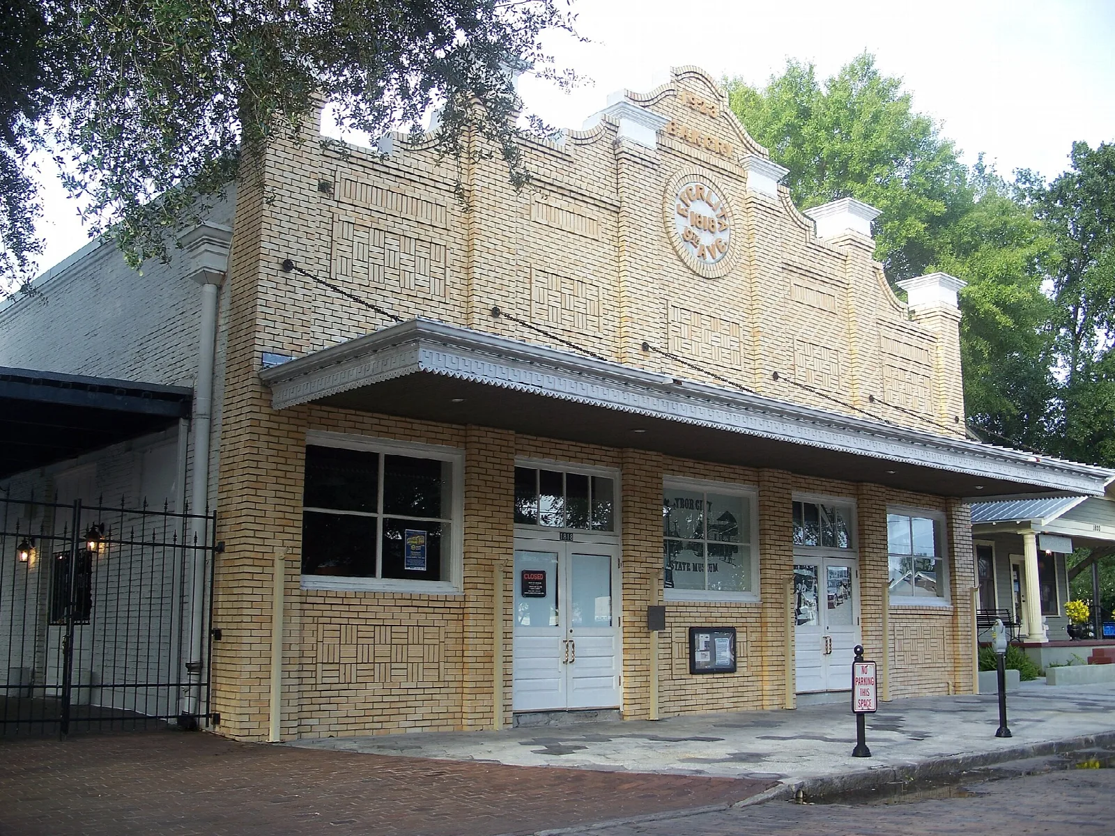 Tan brick museum building with a stepped front and white doors