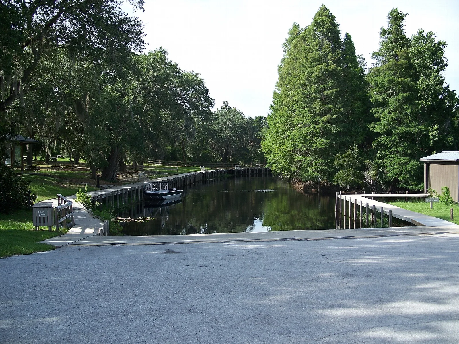Quiet canal beside a paved landing, with tall trees