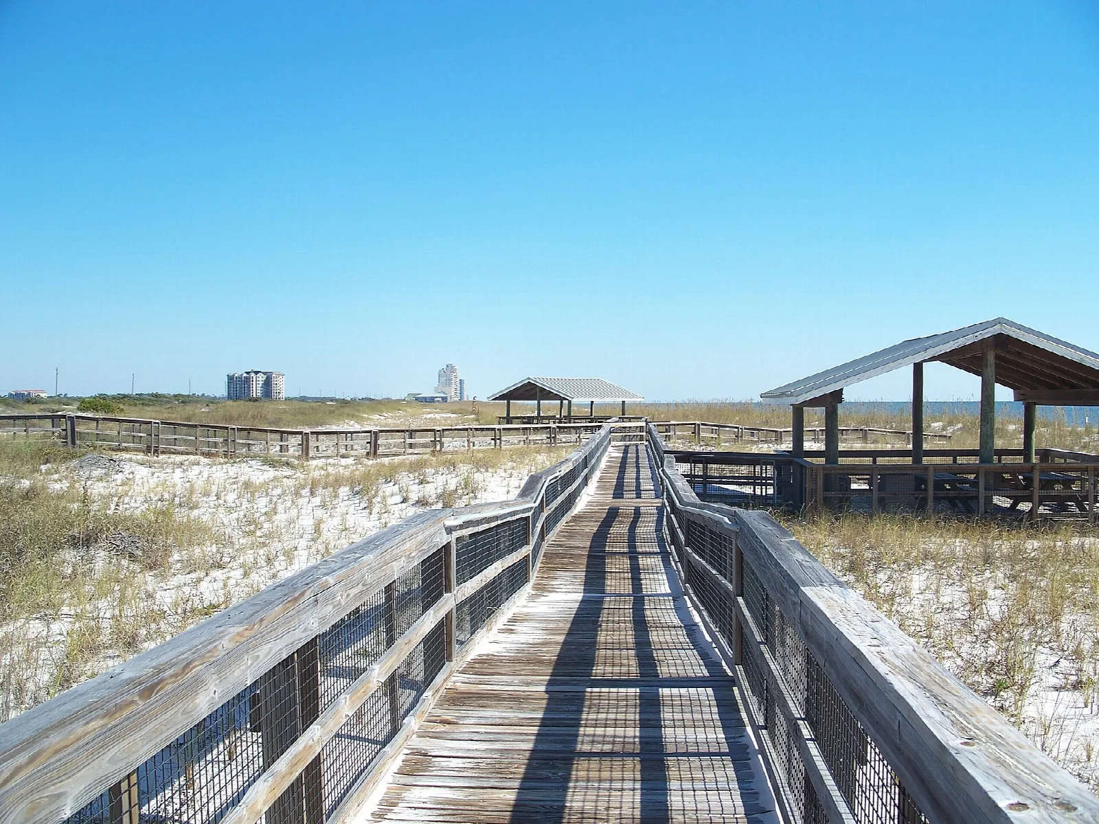 Long wooden boardwalk crossing white dunes