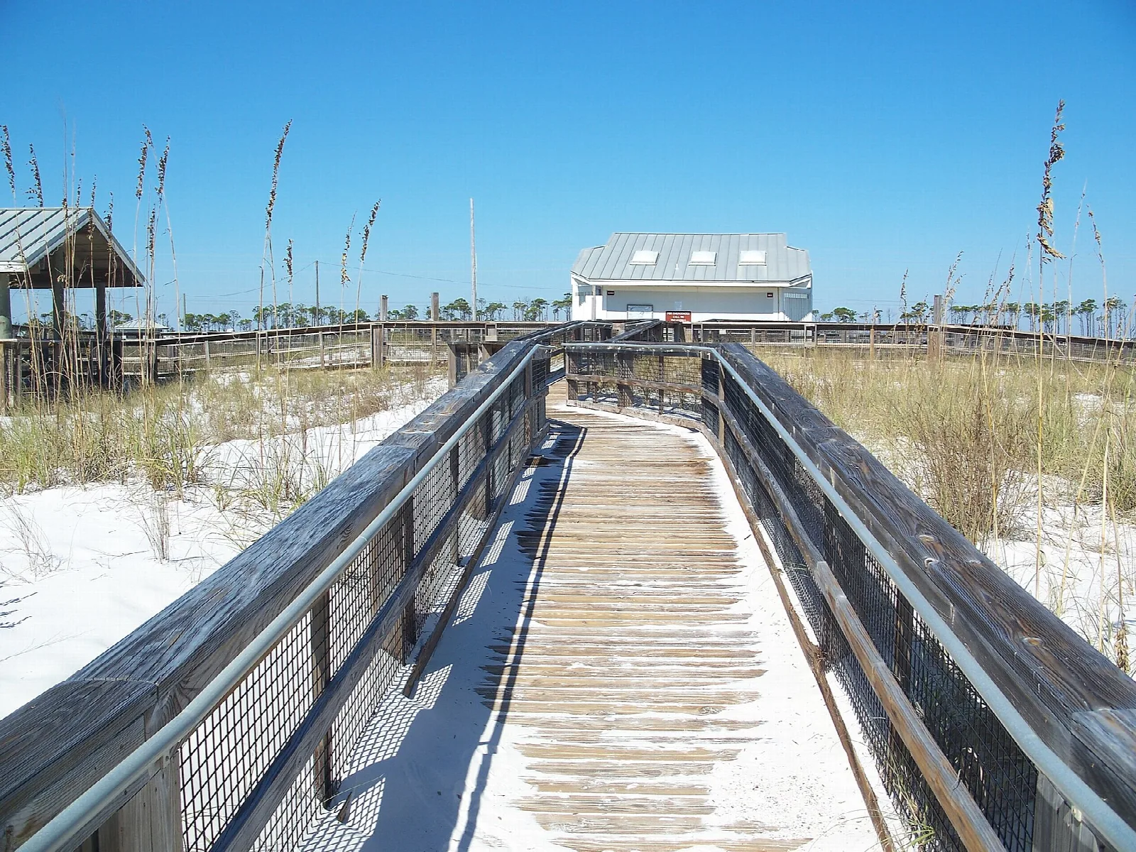 Wooden boardwalk over dunes toward a distant building