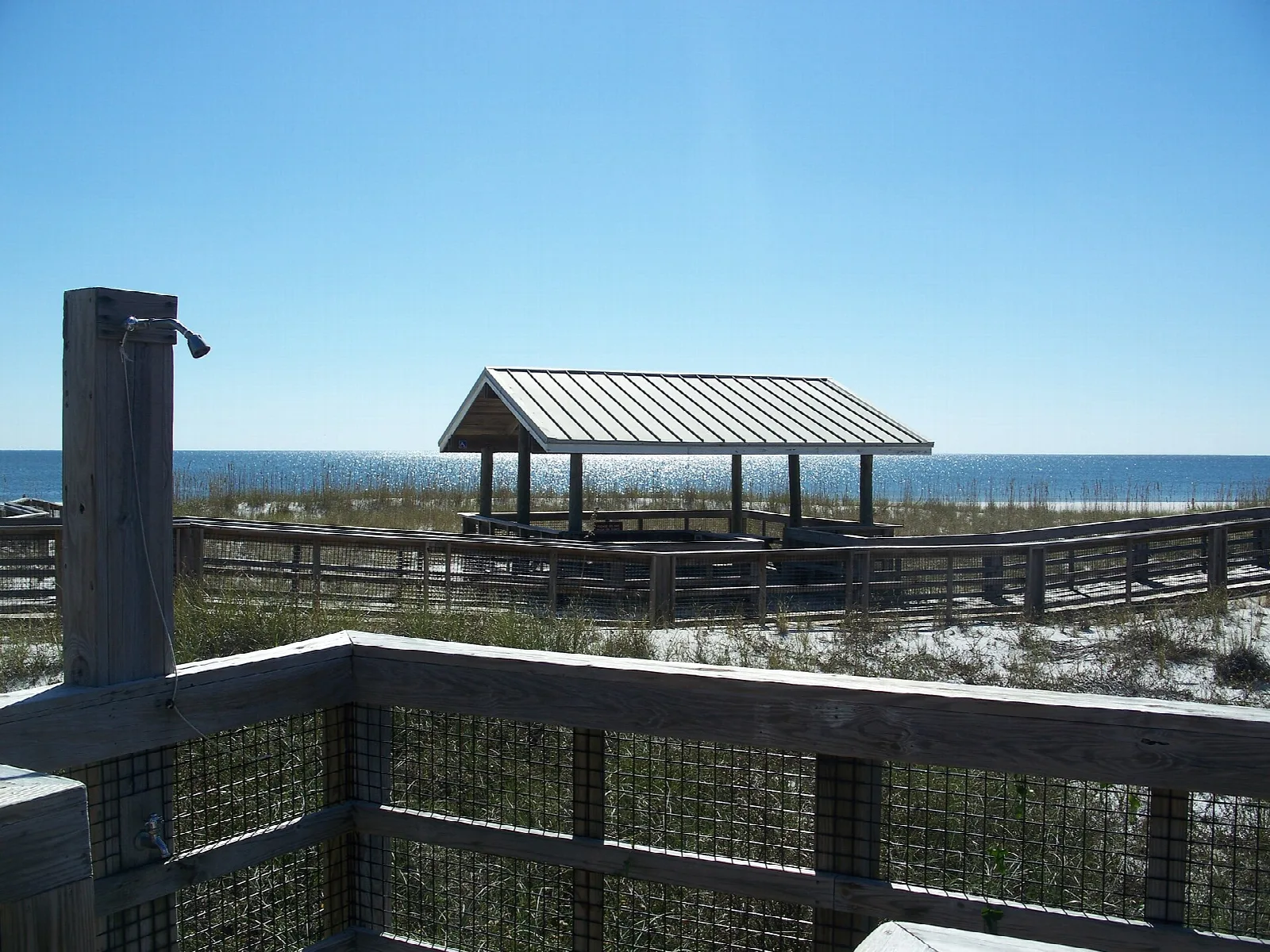 Covered pavilion on a boardwalk over dunes, with the Gulf behind