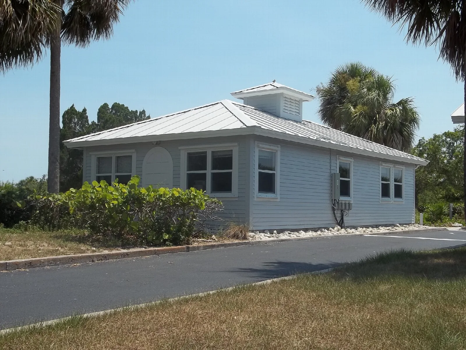 Light blue ranger building with a metal roof beside a road