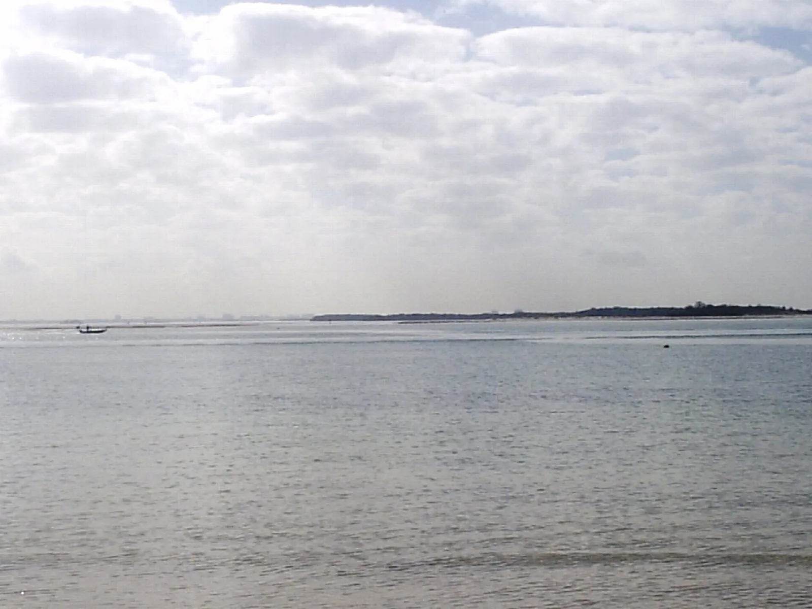 Calm gray water with a low island on the far shore