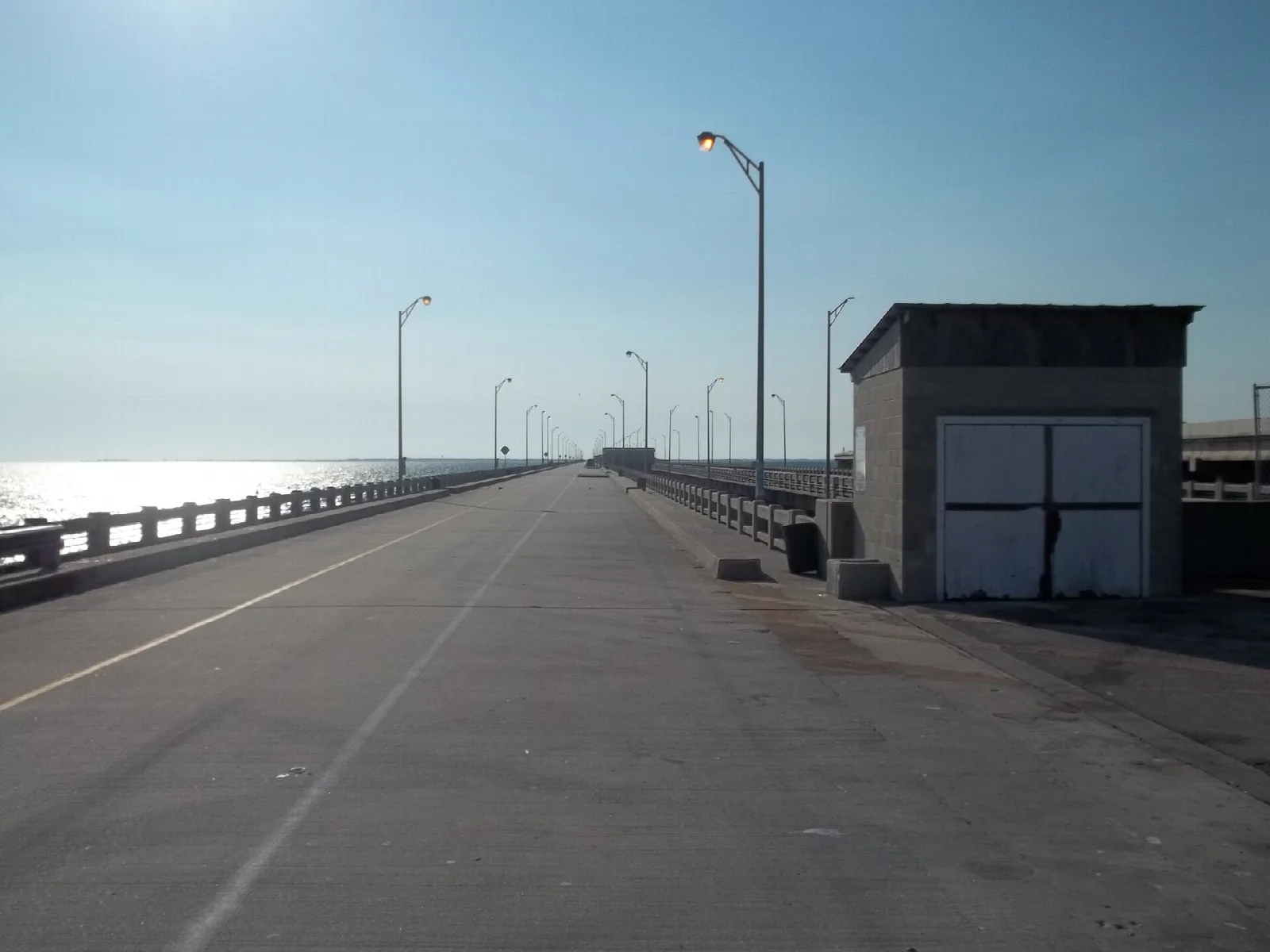 Pier roadway with a small shed and light poles beside the water