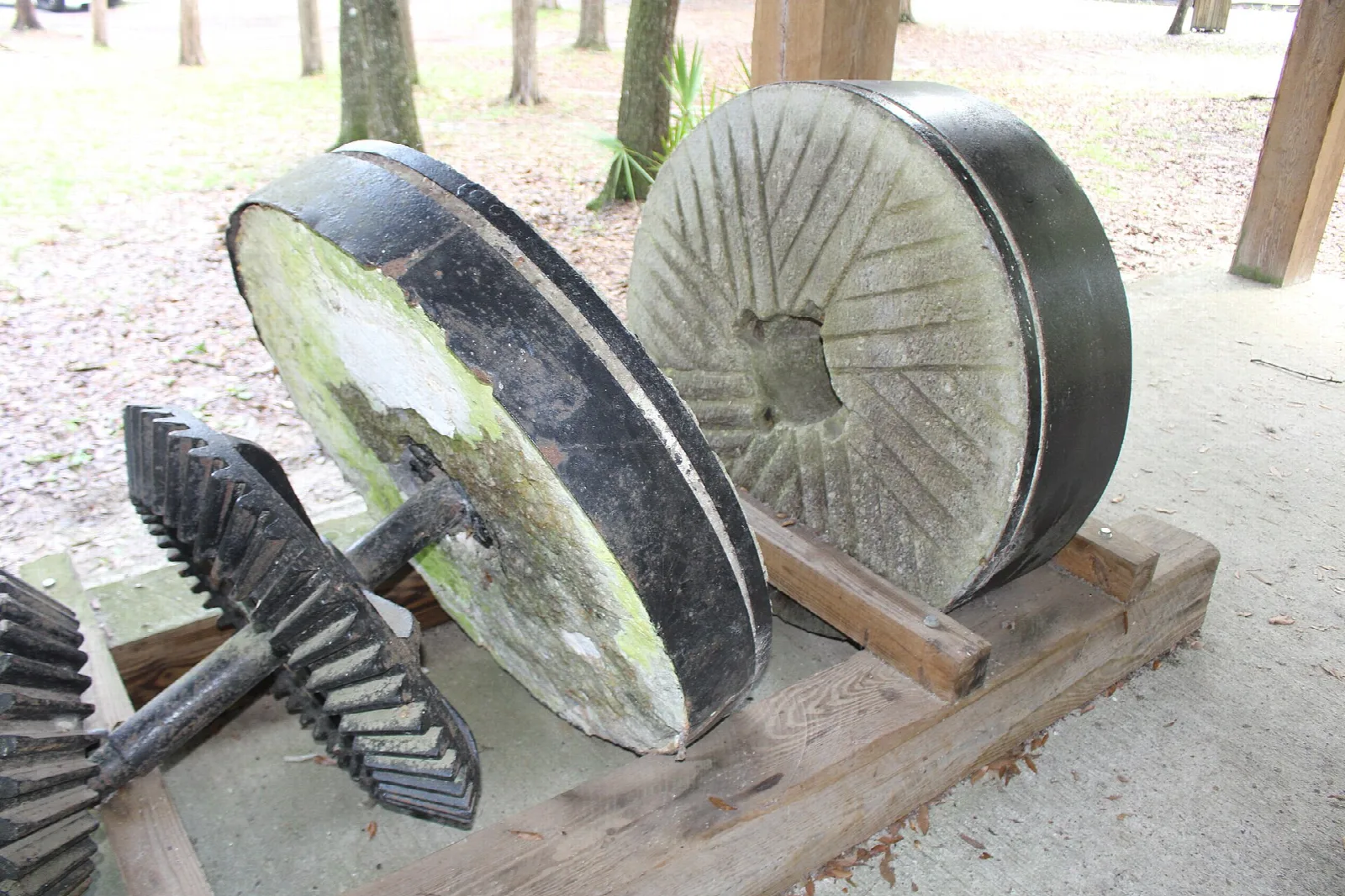 Two old grist stones and gears on a wooden frame