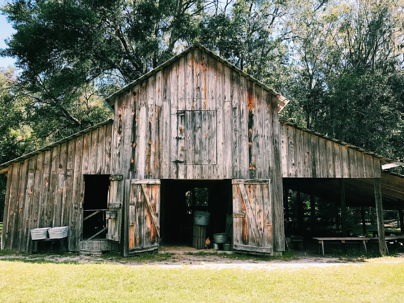 Weathered wood barn with open doors on a grassy farm yard