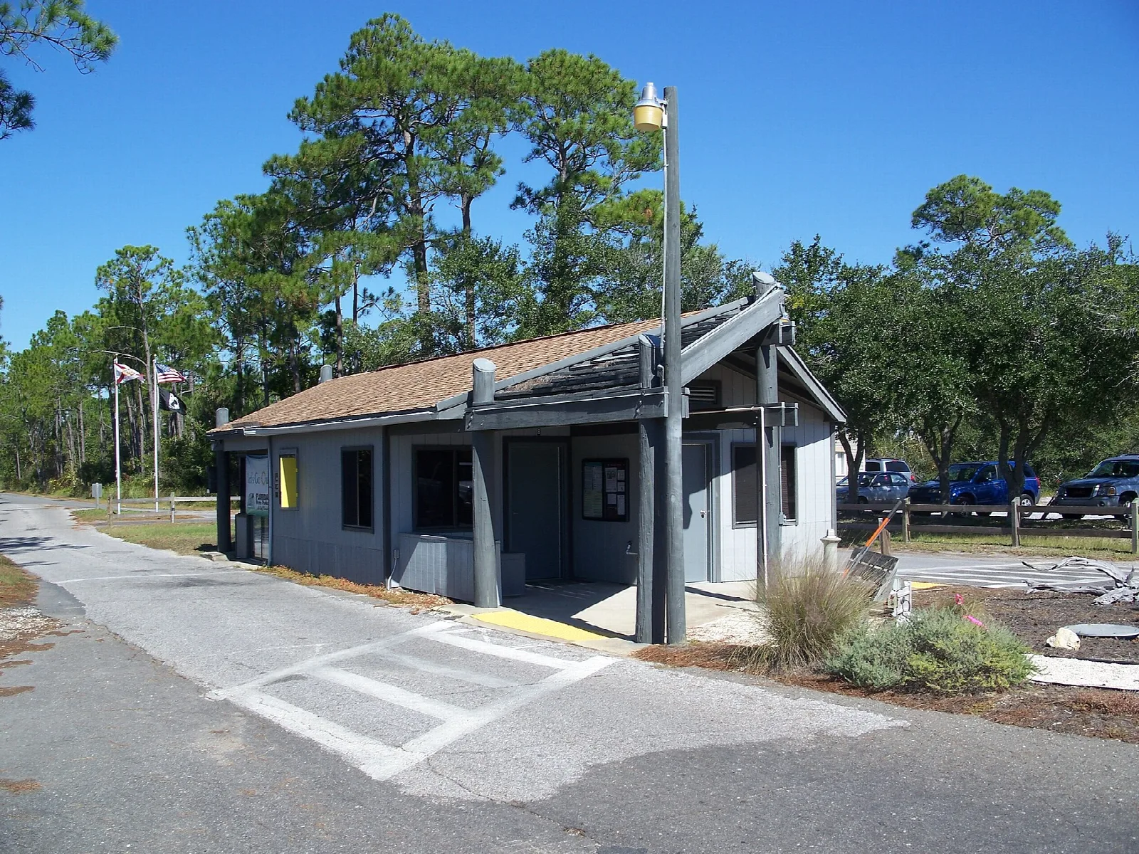 Small gray building with a porch under tall pines