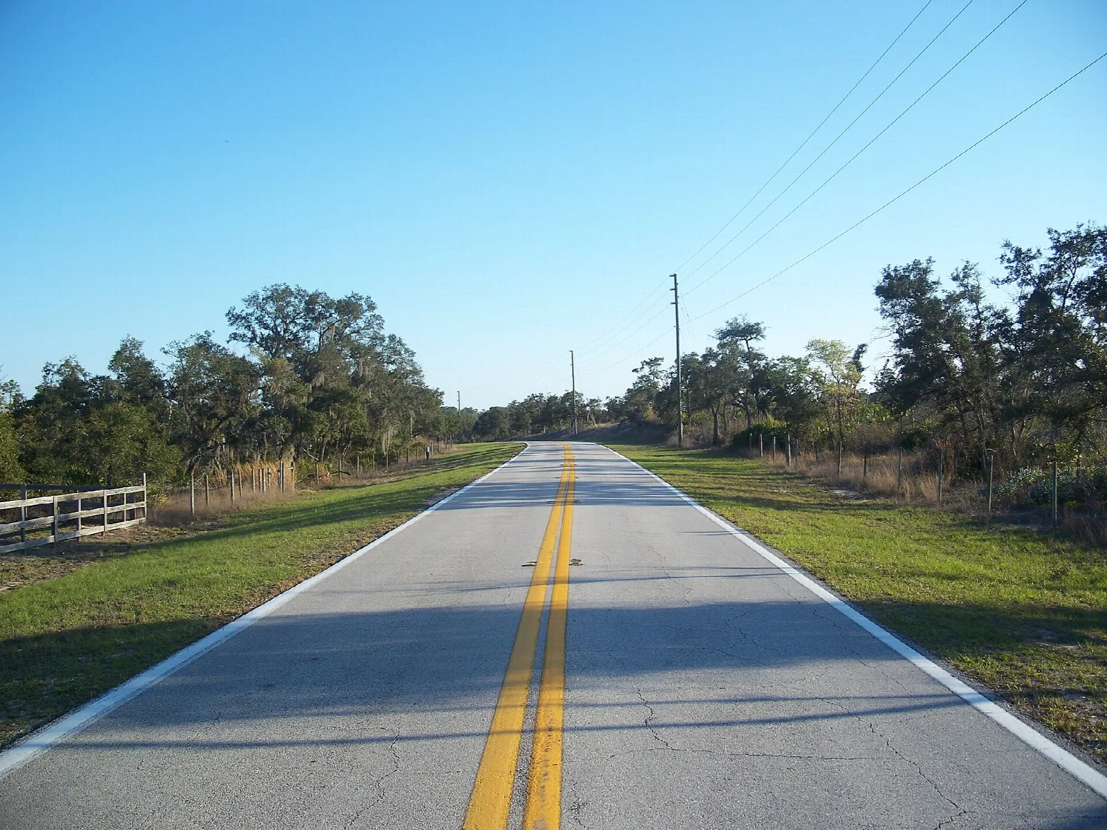 Paved road with a wood fence and trees at the edge
