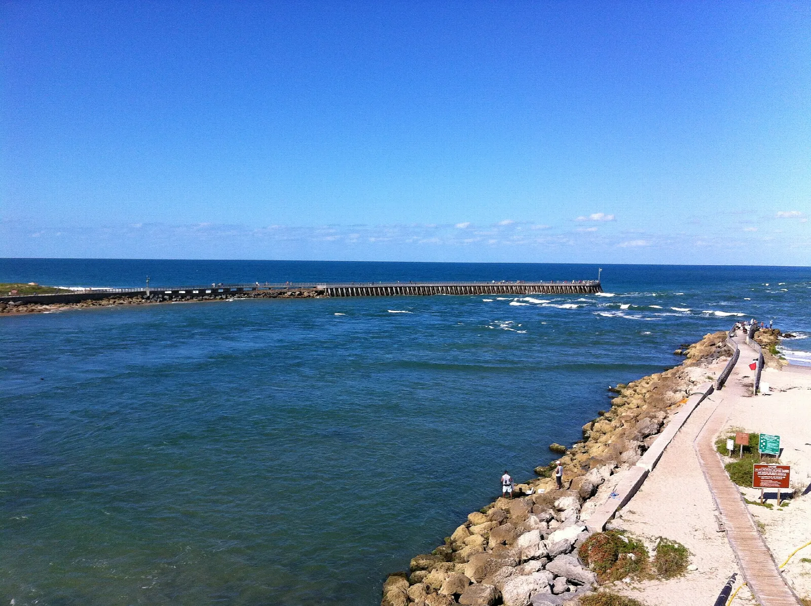 Rock jetty and sandy beach beside the inlet, seen from above